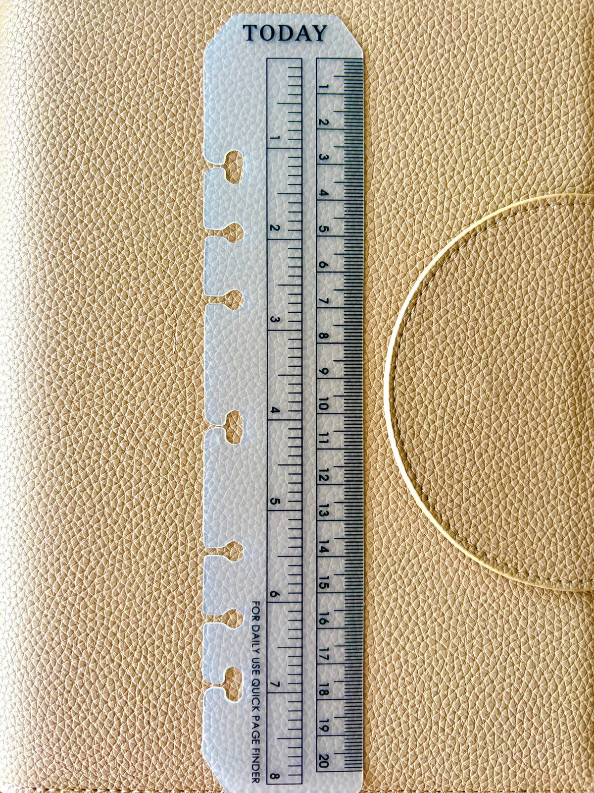 A close-up of a beige textured planner cover with a white plastic divider insert featuring a printed ruler and the word TODAY at the top.
