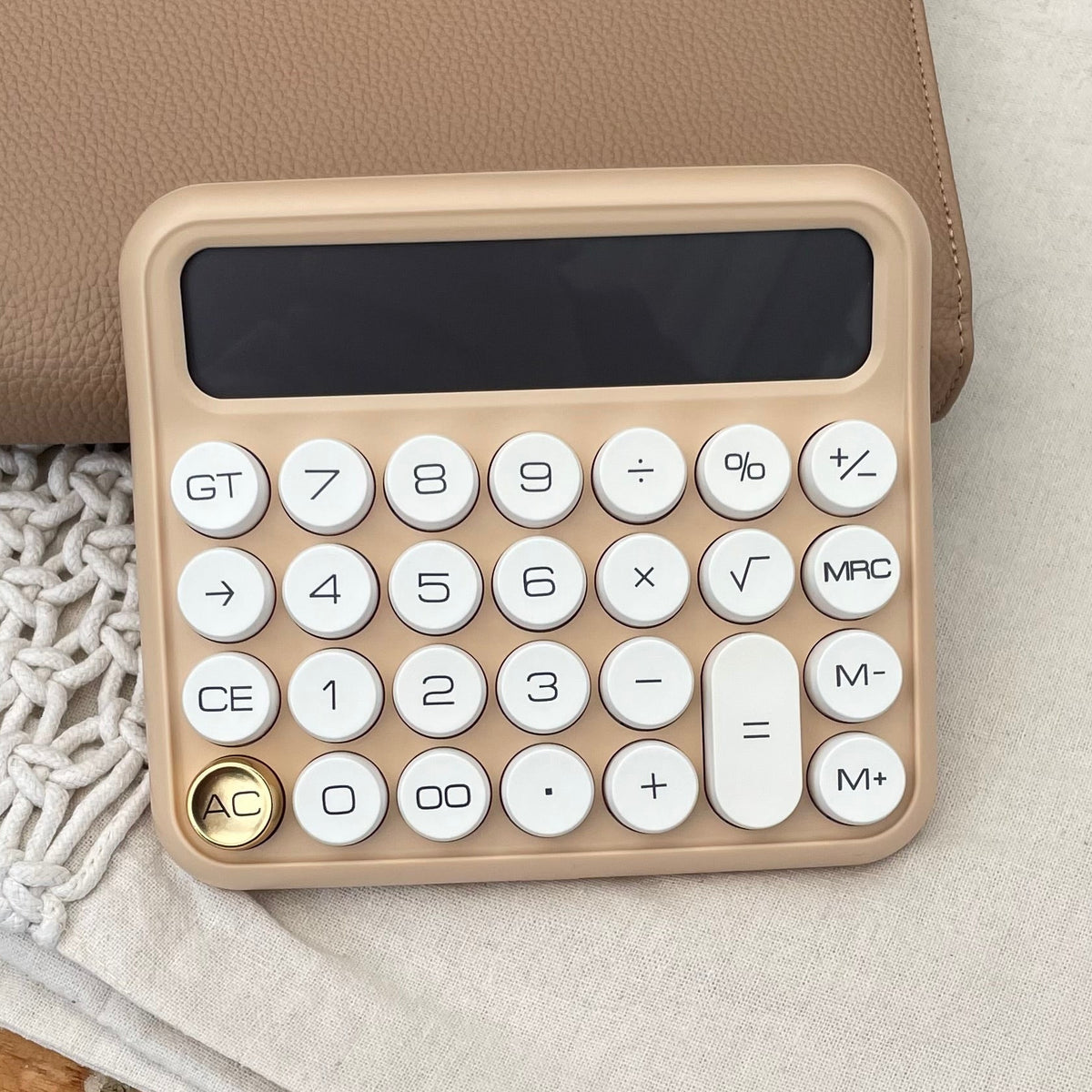 calculator on tan and beige background with gold button