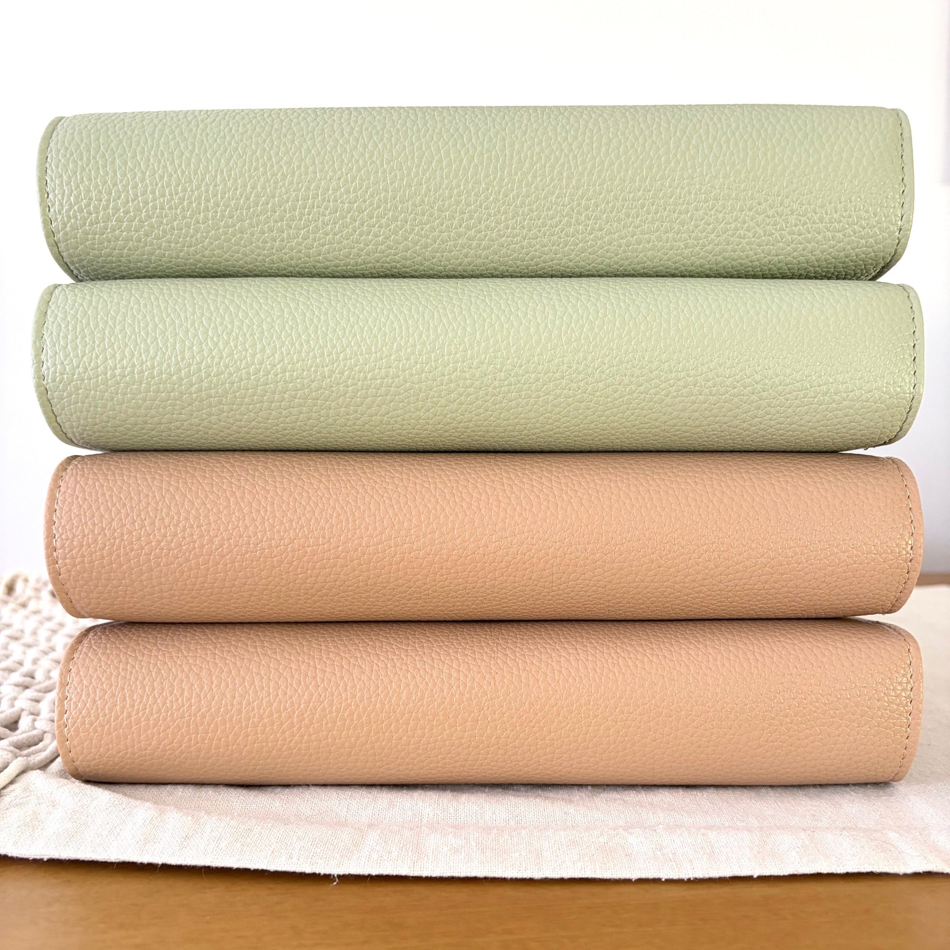 Latte and Sage green binders stacked on a wooden bench