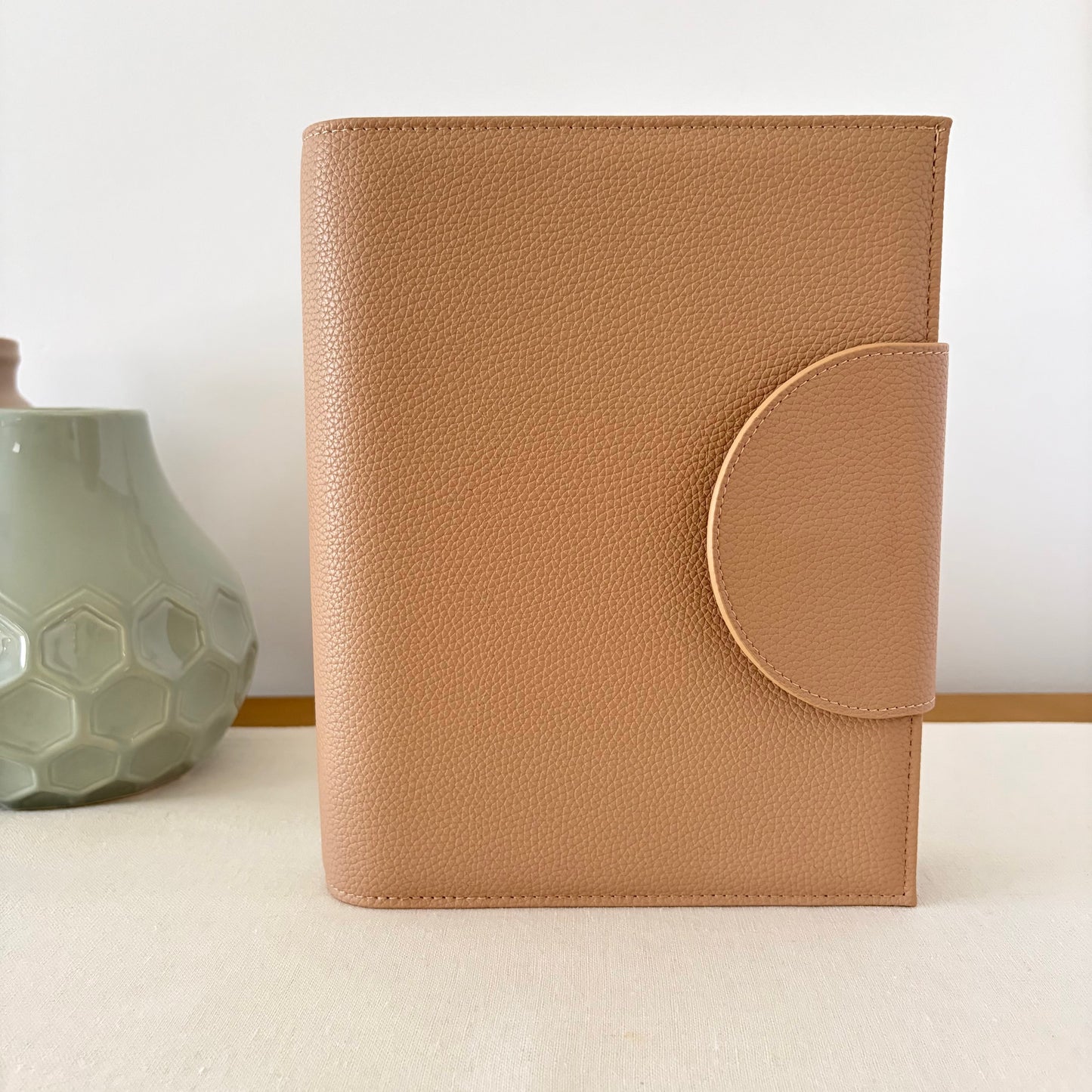 light brown tan leather-bound notebook with a circular design on a white surface with a light background