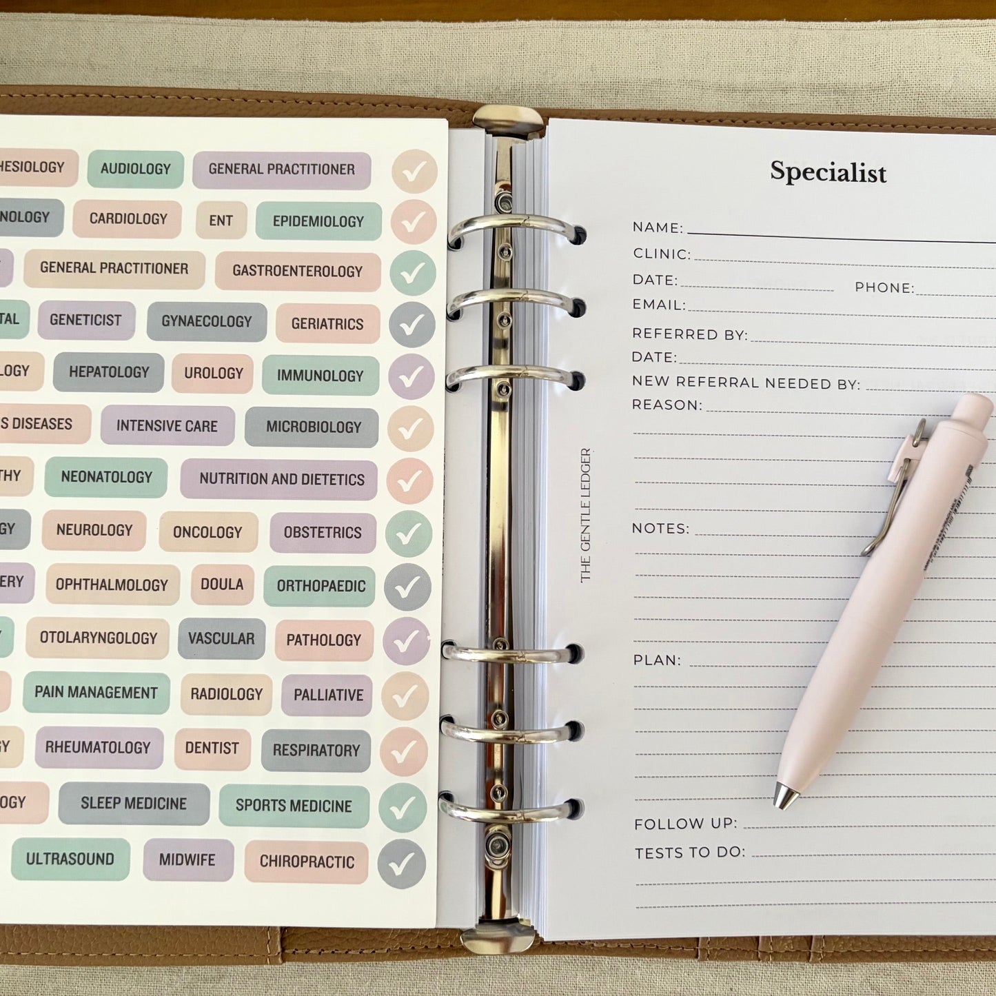 Open planner with medical specialty tabs and a pen on a wooden surface